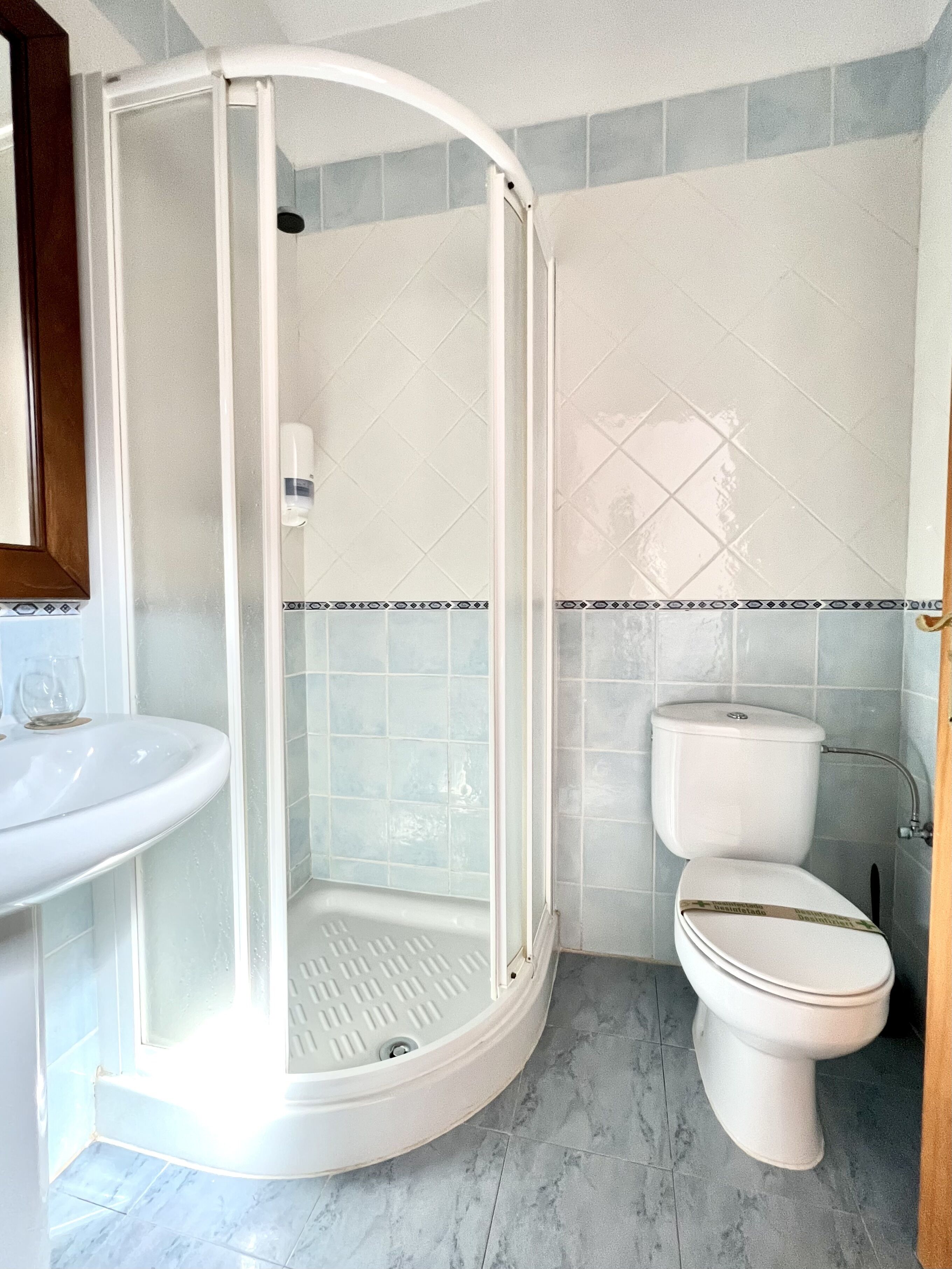 Un baño con ducha de vidrio, inodoro y lavabo.