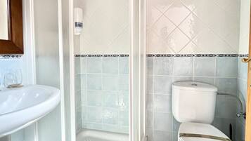 Un baño con ducha de vidrio, inodoro y lavabo.