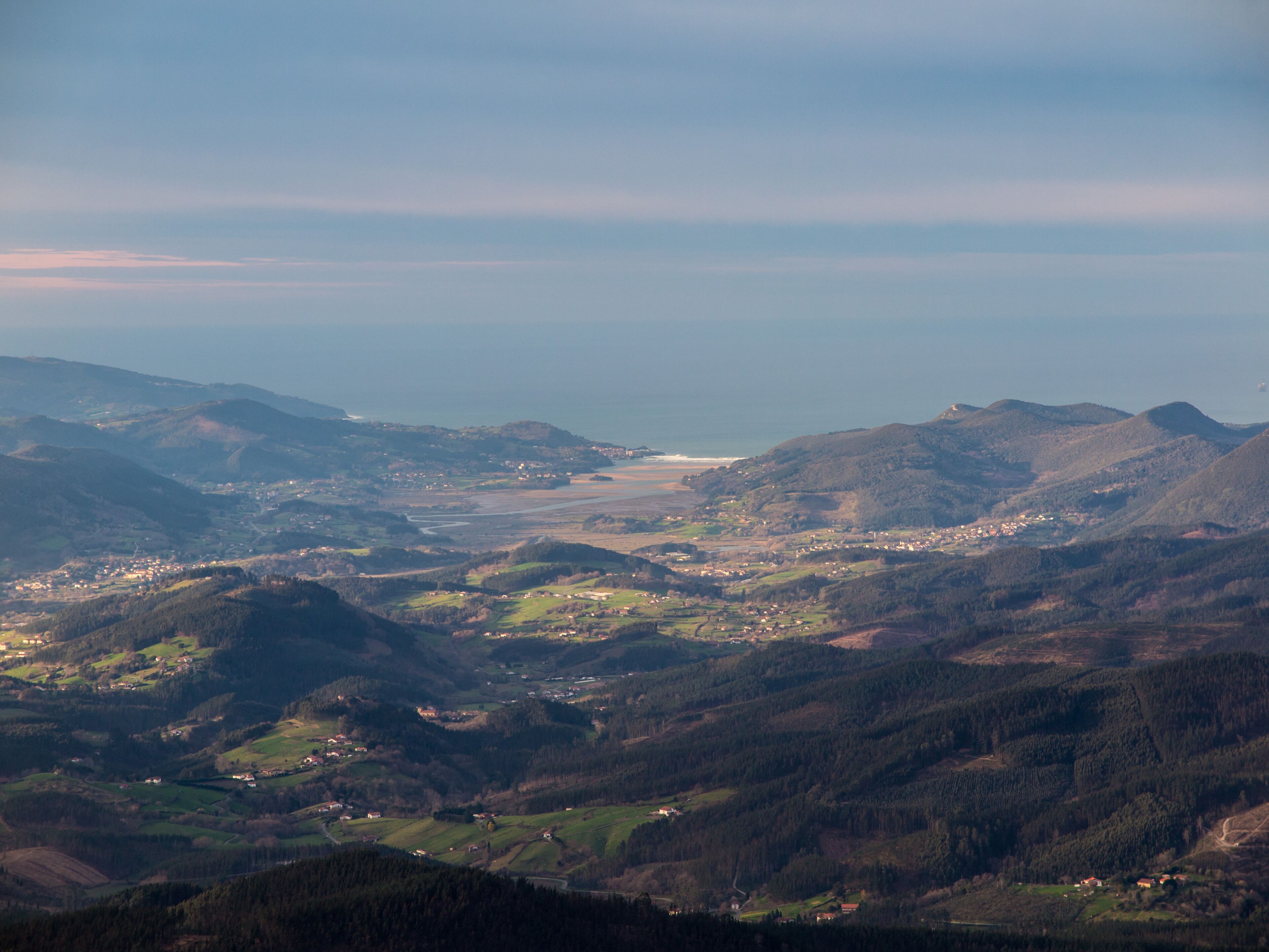 Vista panoràmica d'una vall salpicada d'edificis, envoltada per turons i un riu.