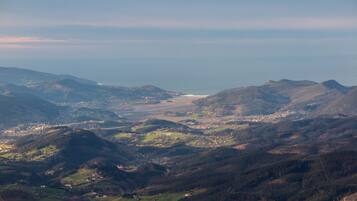 Une vue panoramique d’une vallée parsemée de bâtiments, entourée de collines et traversée par une rivière.