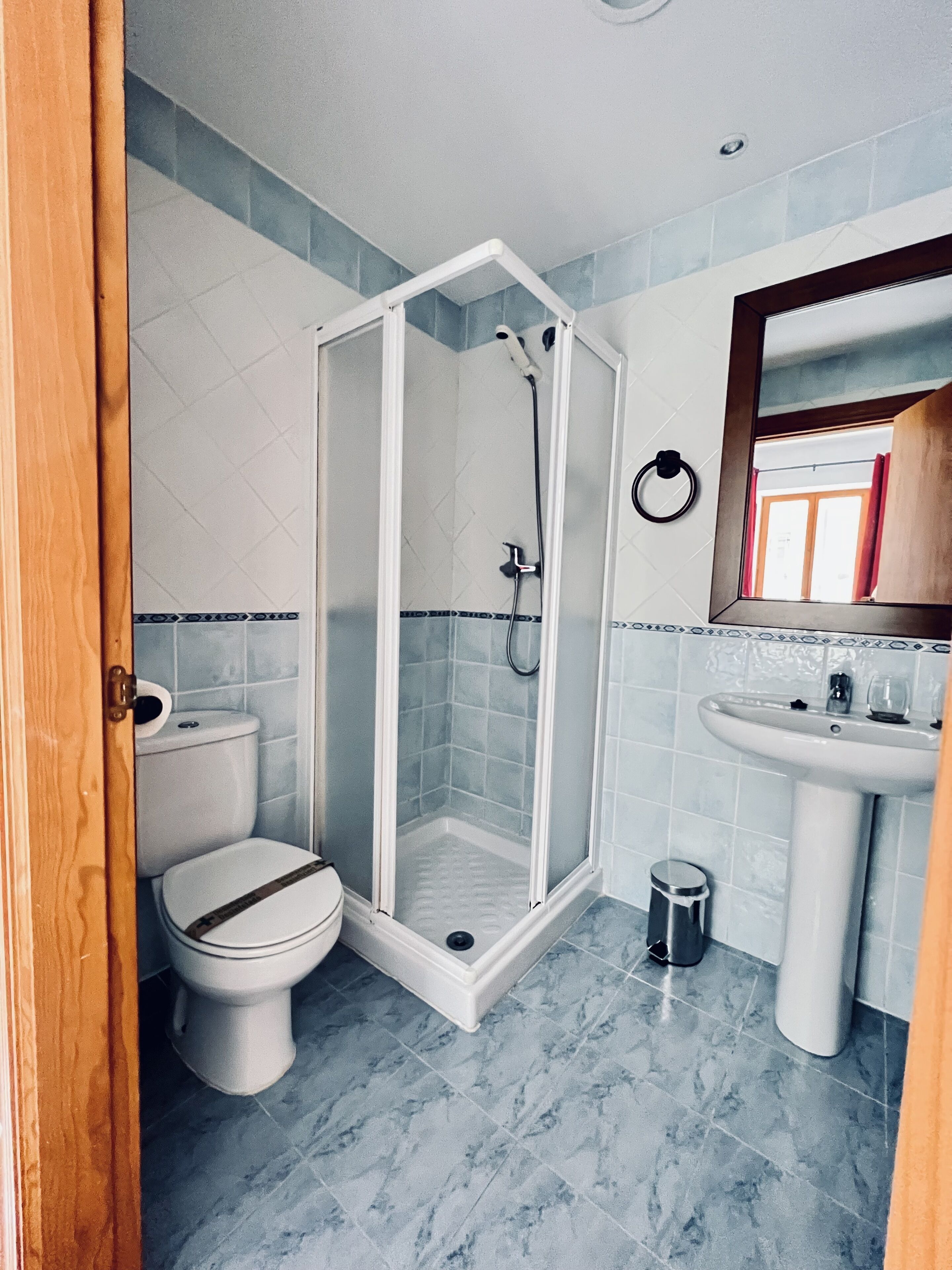 A bathroom with a shower enclosure, toilet, sink, and a mirror.