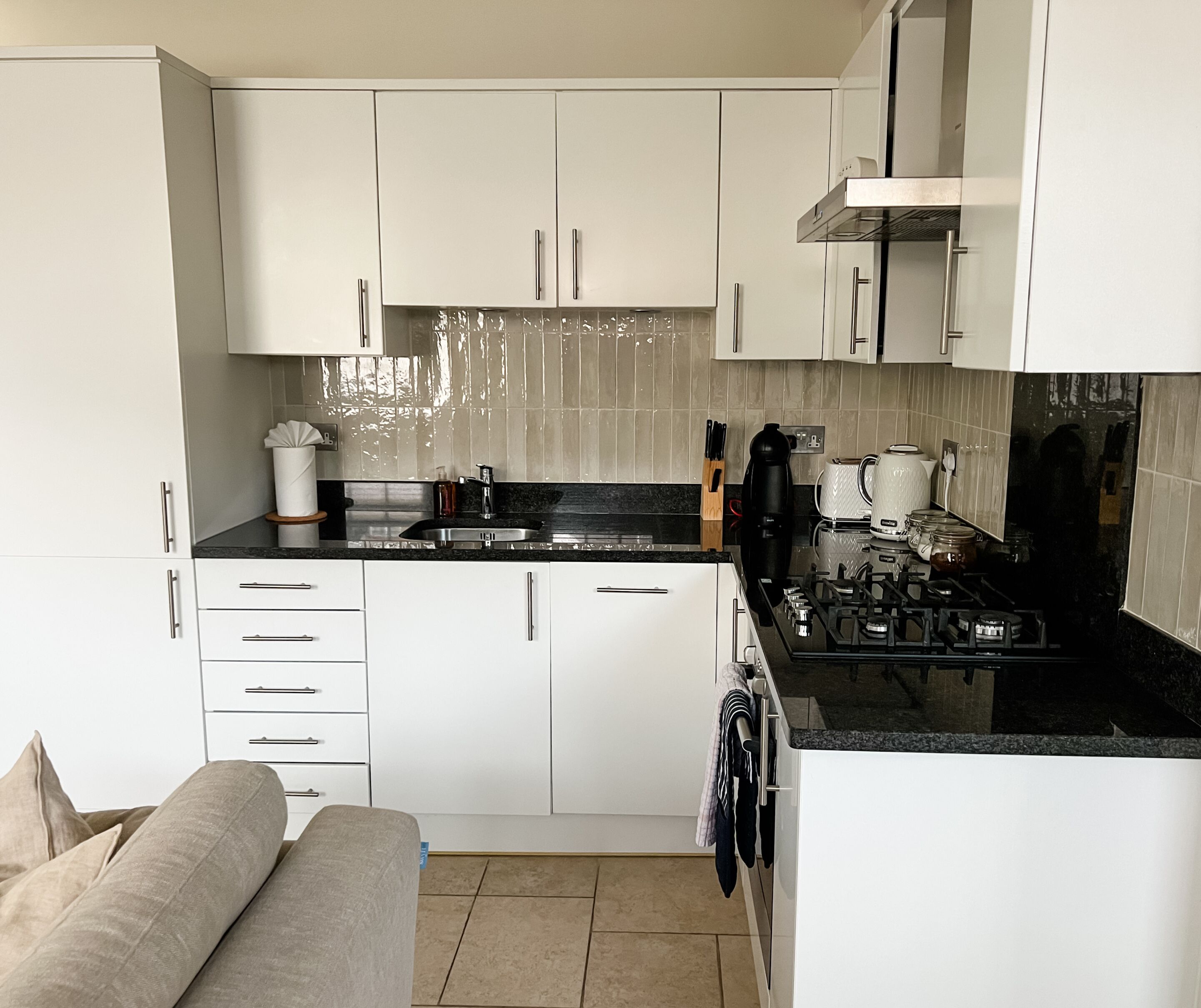 A compact kitchen with white cabinets, a black countertop, and a gas stove.