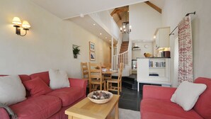 A living room with two red sofas, a wooden coffee table, and a dining area with a wooden table and chairs. - The Barn, Park Farm near Chew Magna, Bristol (Bristol)