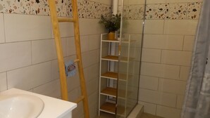Ein Badezimmer mit einem weißen Waschbecken, einem gelben Seifenspender und einer Holzleiter, die an der Wand lehnt.