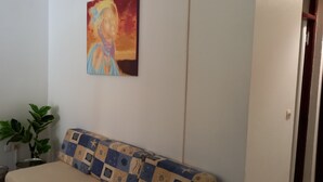 Ein Zimmer mit einer gemusterten Couch, einer Topfpflanze und einem Bild an der Wand.