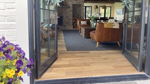 Ein modernes Wohnzimmer mit Kamin aus Ziegelsteinen, Ledersofas und einer Glastür.