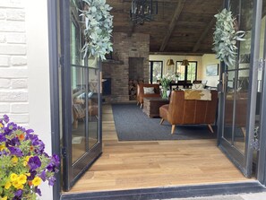 Cozy living room with a brick fireplace, leather sofas, and a glass door entrance.