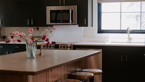 Eine moderne Küche mit einer zentralen Kochinsel, Barhocker und einer Blumenvase.