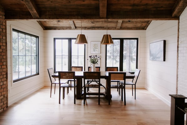 Cozy dining area with a wooden table and chairs, surrounded by artwork and a potted plant.