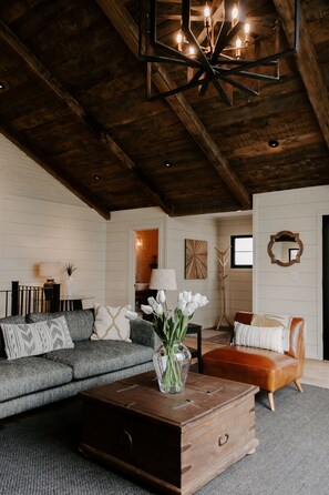 Relax in this inviting living room with a high ceiling, dark coffee table, and comfortable seating areas.