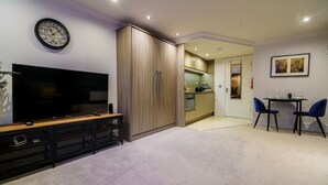 Un salon moderne doté d’un téléviseur à écran plat, d’un meuble en bois et d’un coin repas comprenant deux chaises et une table.