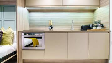 Una kitchenette compacta con horno integrado, cafetera y lavabo.