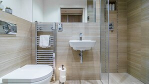 Une salle de bain moderne équipée de toilettes, d’un lavabo et d’une douche à parois en verre.