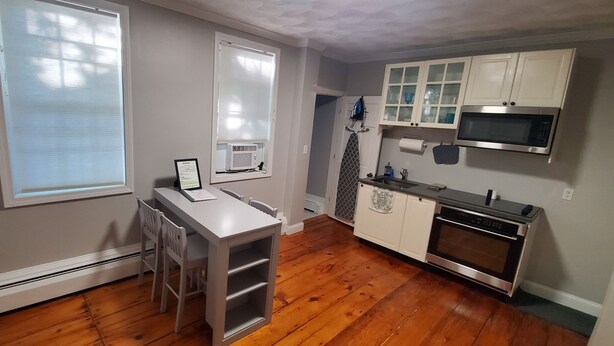 A kitchen with wooden flooring, white cabinets, a microwave, and an oven. - Spacious Studio near downtown (Newport)