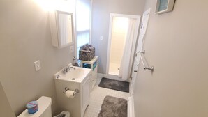A narrow bathroom with a toilet, sink, and a small window. - Spacious Studio near downtown (Newport)