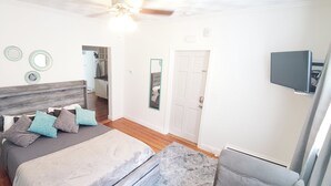 A bedroom with a bed, bedside table, lamp, ceiling fan, and a TV mounted on the wall. - Spacious Studio near downtown (Newport)