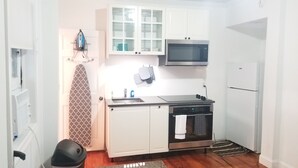 A compact kitchen with white cabinets, a microwave, an oven, and a kettle. - Spacious Studio near downtown (Newport)