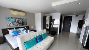 Une chambre d’hôtel moderne équipée d’un grand lit, d’un canapé, d’un bureau et d’un coin cuisine.
