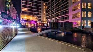 Un espace piscine d’hôtel au design moderne, comprenant un bord de piscine incurvé et un coin salon offrant une vue sur la piscine.