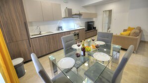 Une cuisine moderne avec un coin repas comprenant une table en verre, des chaises et un canapé.