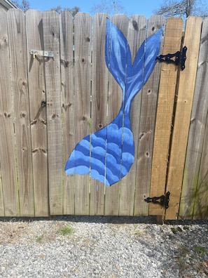 Surrounded by a charming fence with a whimsical mermaid tail design, this outdoor space invites relaxation.