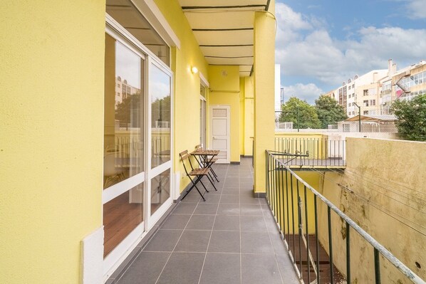 Un edificio amarillo con balcón, una mesa y sillas, y vistas de la ciudad.