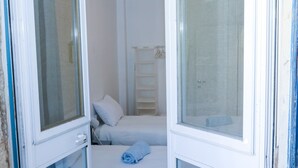 Et lille, rent værelse med to senge, et vindue og et hvidt skab.