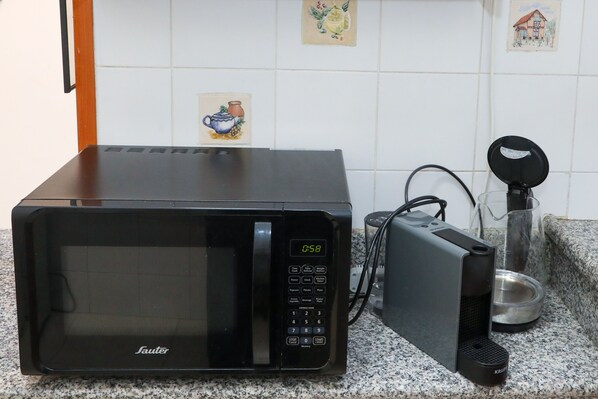 A black microwave oven with a digital display on a granite countertop.