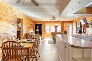 Cozy cabin interior with a dining table for four, comfortable sofa, and modern kitchen amenities.