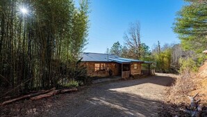 A rustic wooden cabin with a gravel driveway, surrounded by dense bamboo and trees. - Sheep’s Knob Refuge- ..Take refuge in Him. Ps 34:8 (Franklin)