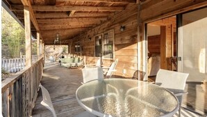 A wooden deck with a glass table and chairs, overlooking a forested area. - Sheep’s Knob Refuge- ..Take refuge in Him. Ps 34:8 (Franklin)