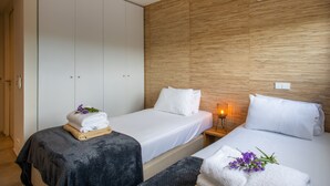Een hotelkamer met twee bedden, een houten hoofdeinde, een airconditioning en een bedlampje.