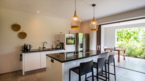 Een moderne keuken met een centraal eiland, barkrukken en hanglampen.