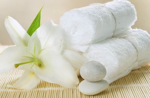 A white lily, rolled white towels, and smooth stones on a bamboo mat. - Me Gustas Downtown Hotel (Ho Chi Minh City)