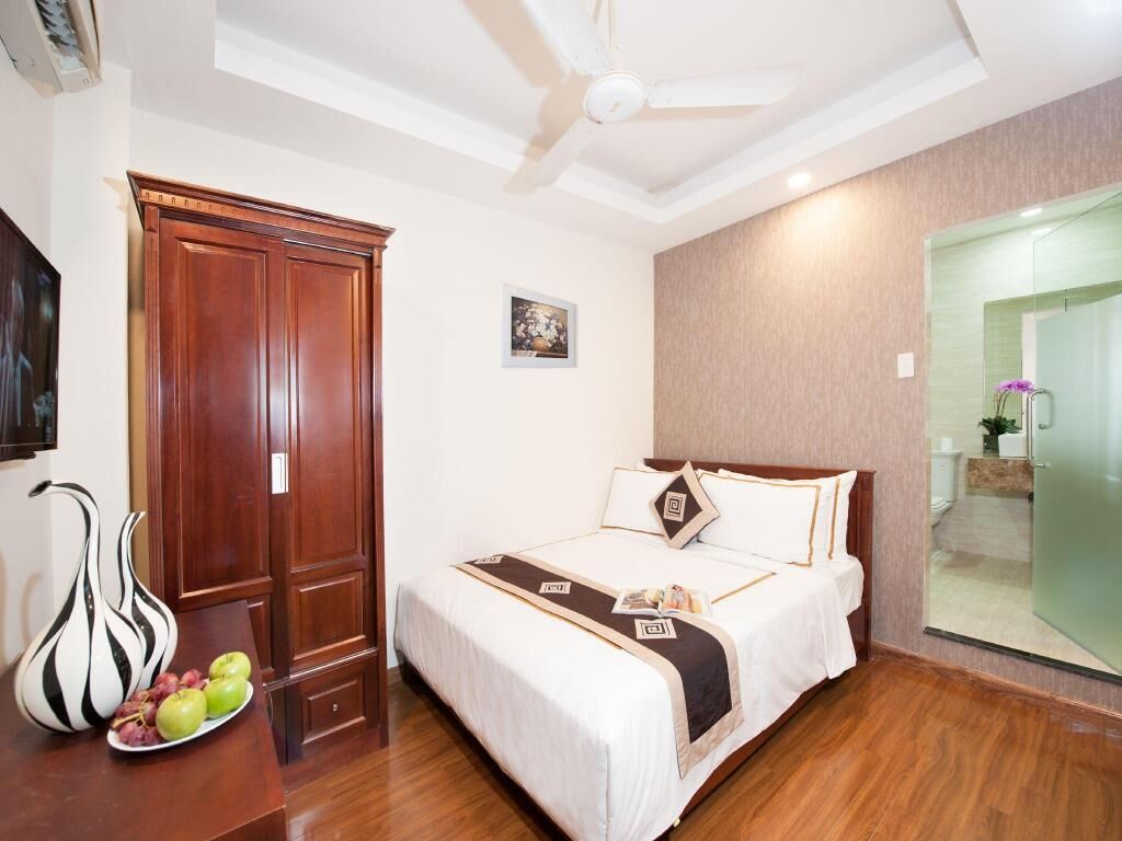 A hotel room with a bed, wooden wardrobe, and a ceiling fan.