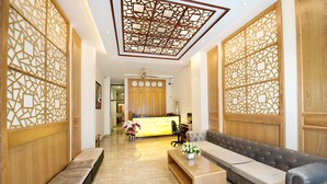 A hotel lobby with a reception desk, seating area, and decorative wooden panels. - Me Gustas Downtown Hotel (Ho Chi Minh City)
