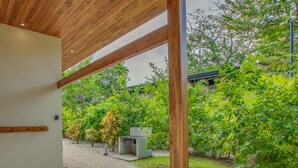 Un espace extérieur moderne doté d’un plafond en bois, d’une douche et d’un jardin agrémenté de diverses plantes et d’une petite structure.