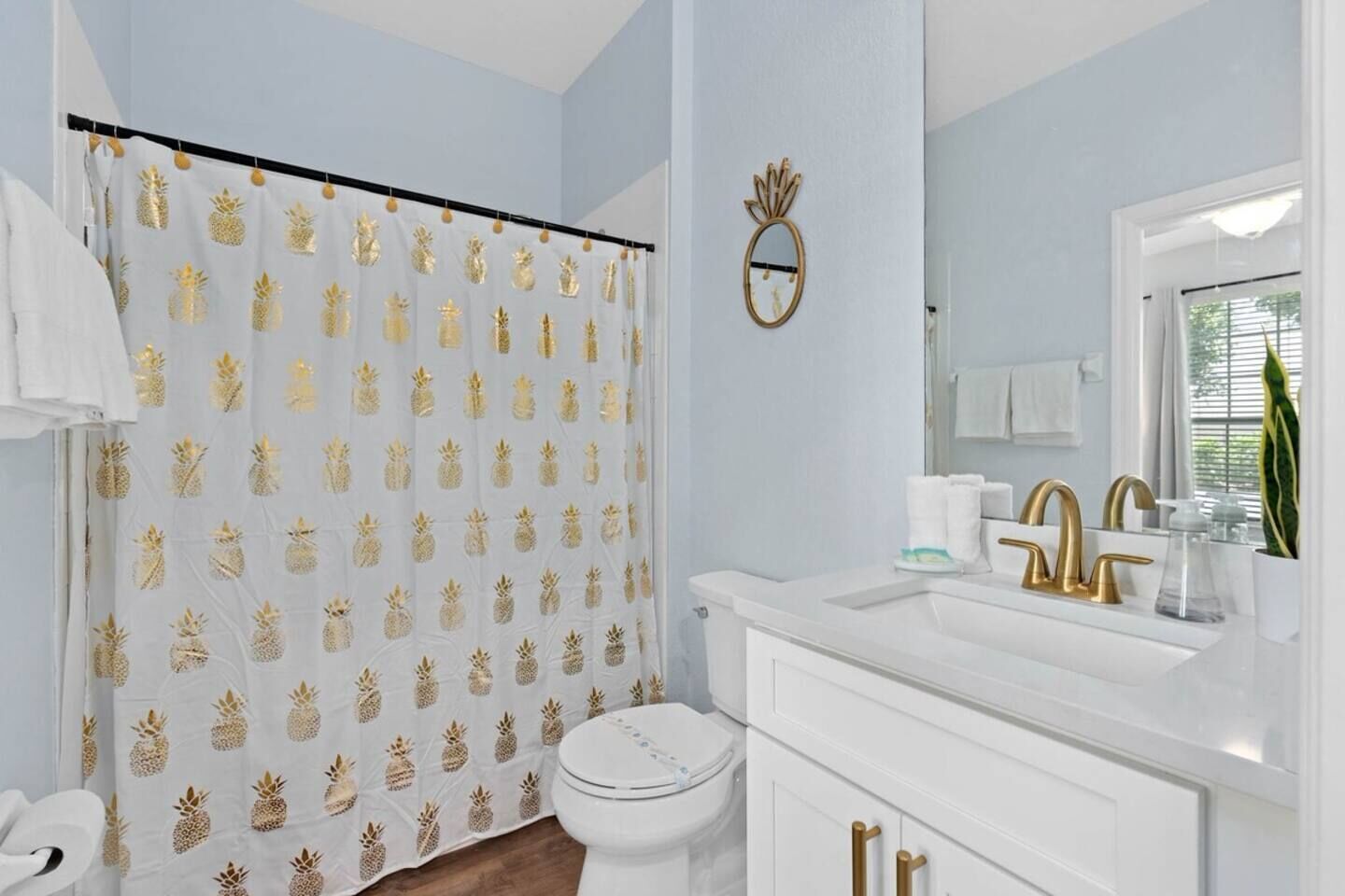 A bathroom with a toilet, sink, and shower curtain with a pineapple pattern.