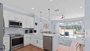 A modern kitchen with white cabinetry, stainless steel appliances, and a large island.