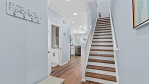 A hallway with a wooden staircase, white walls, and a bench.