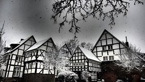 A traditional half-timbered house with a symmetrical facade, snow-covered ground, and bare trees. - Fünf Giebel Eck in der Freiheit am Ruhrtalradweg (Wetter)
