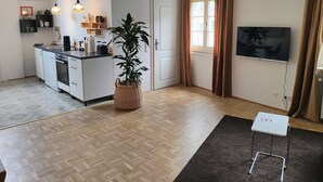 A modern kitchen with white cabinets, a built-in oven, and a dining area with a small table and chair. - Fünf Giebel Eck in der Freiheit am Ruhrtalradweg (Wetter)