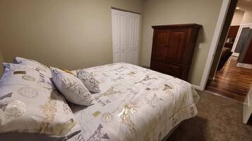 A bedroom with a bed, a wardrobe, and a door leading to another room.