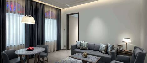 A modern living room with a sofa, two armchairs, a coffee table, and a dining table.