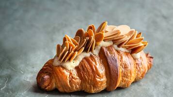 Un croissant con almendras en la parte superior, sobre una superficie texturizada.
