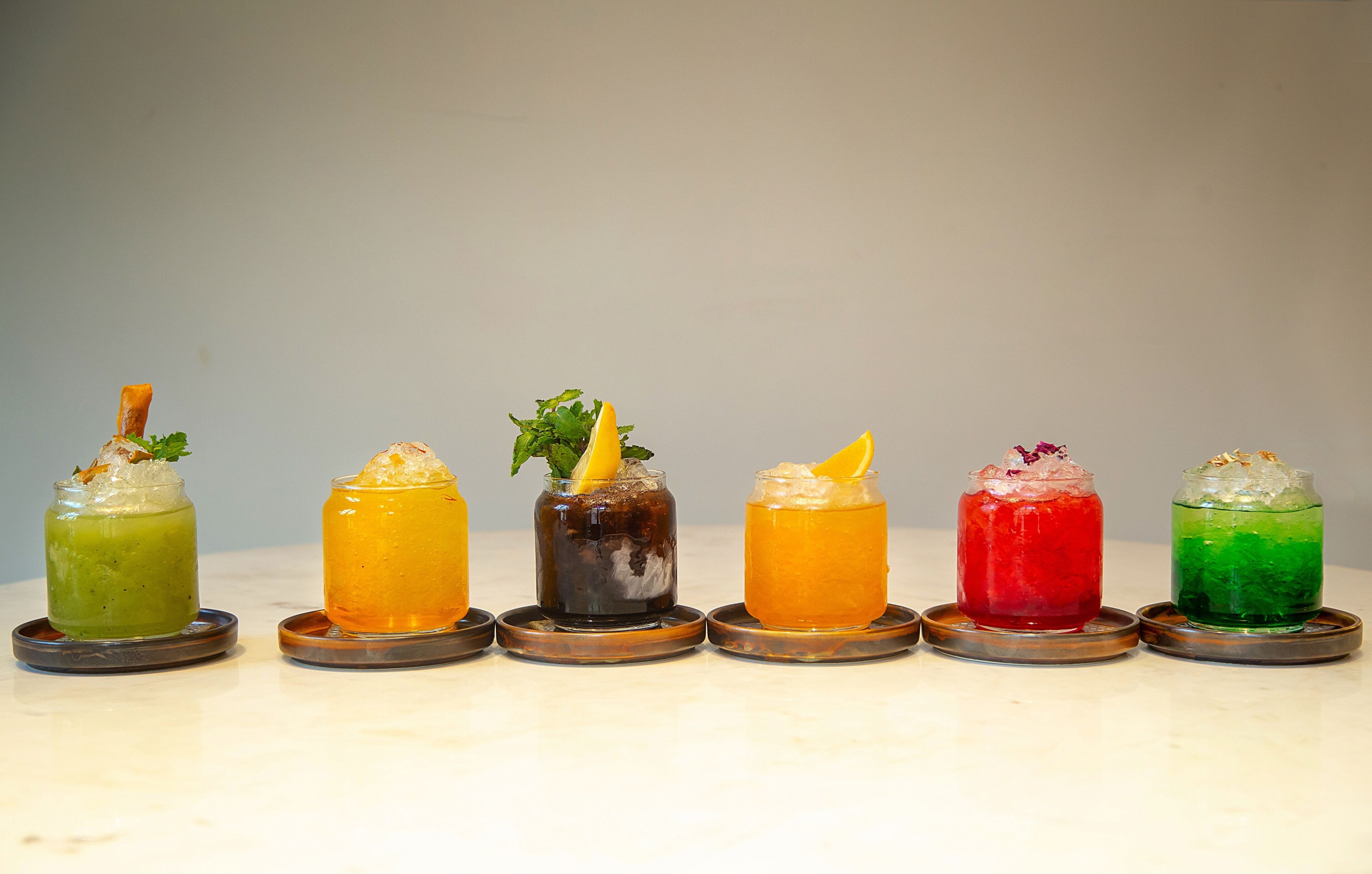 Six colorful drinks on a marble surface.