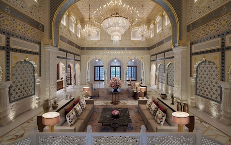 A luxurious lobby with ornate decor, chandeliers, and seating areas.
