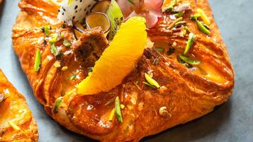 A dessert with orange slices, dragon fruit, and pistachios on a pastry.