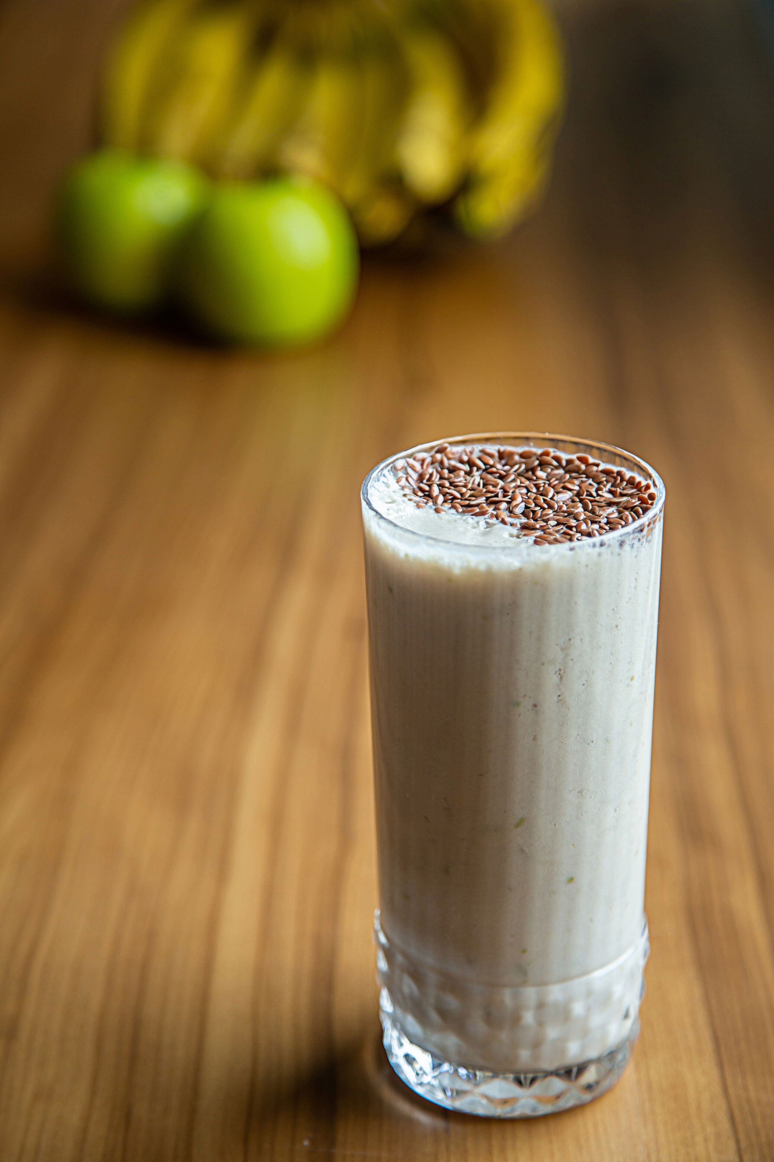 Ein hoher Milchshake mit einer Topping aus Samen, auf einer Holzoberfläche platziert.