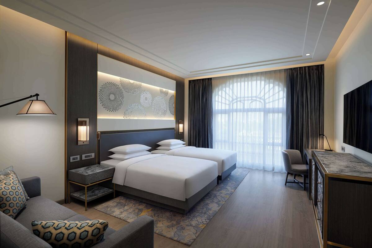 Une chambre d’hôtel moderne, dotée d’un grand lit, d’un bureau et d’une télévision.